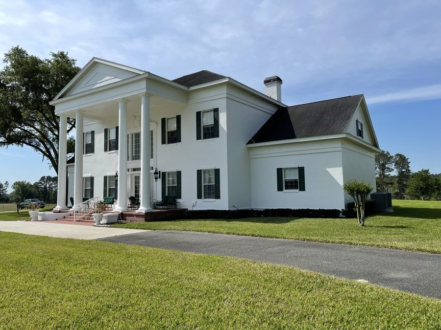 Residential exterior painting project with white siding and dark shutters