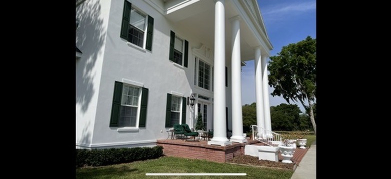 White residential entry with columns and green shutters