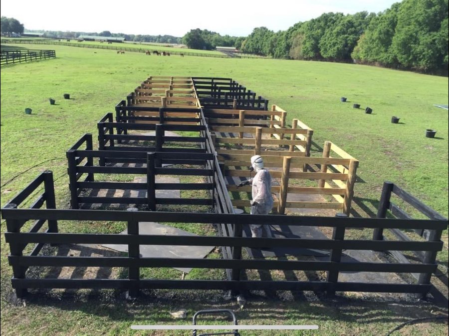 Crew painting a farm fence around pasture pens