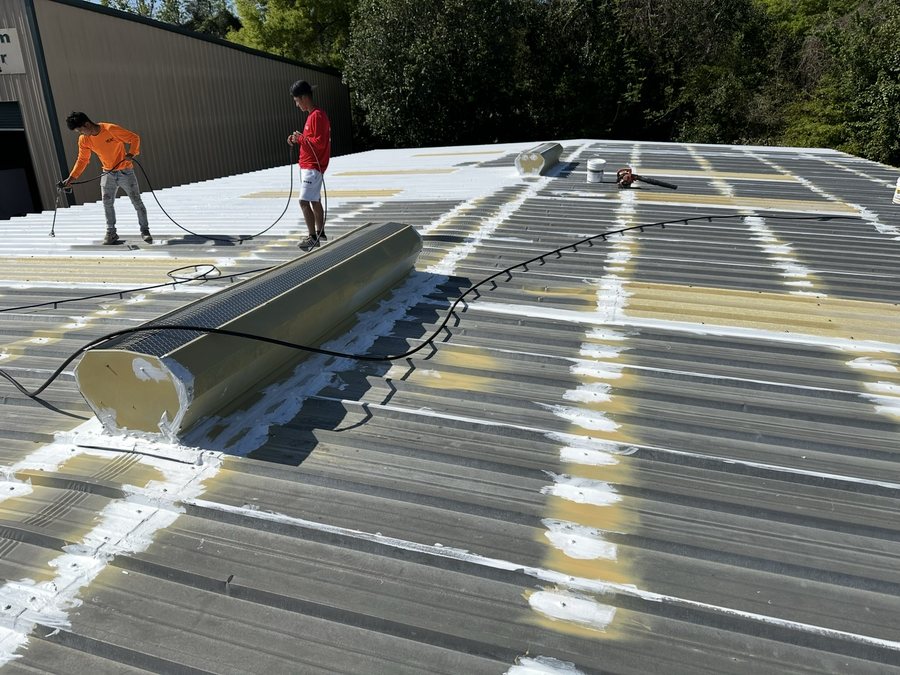 Crew applying liquid coating on a metal roof