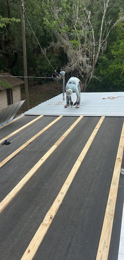 Metal roofing project photo - worker installing metal roof