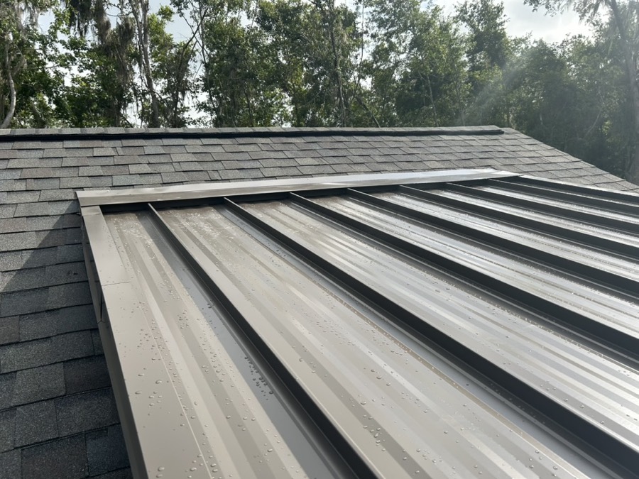 Metal roof panels finished beneath an existing shingle roof transition