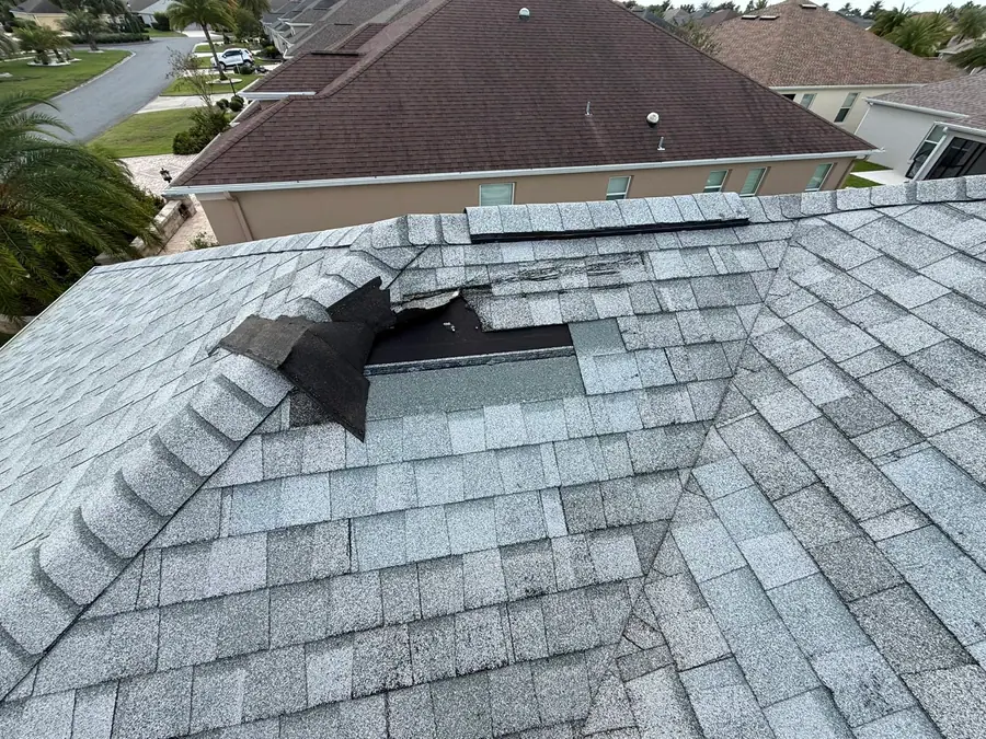 Storm-damaged ridge shingles on a shingle roof