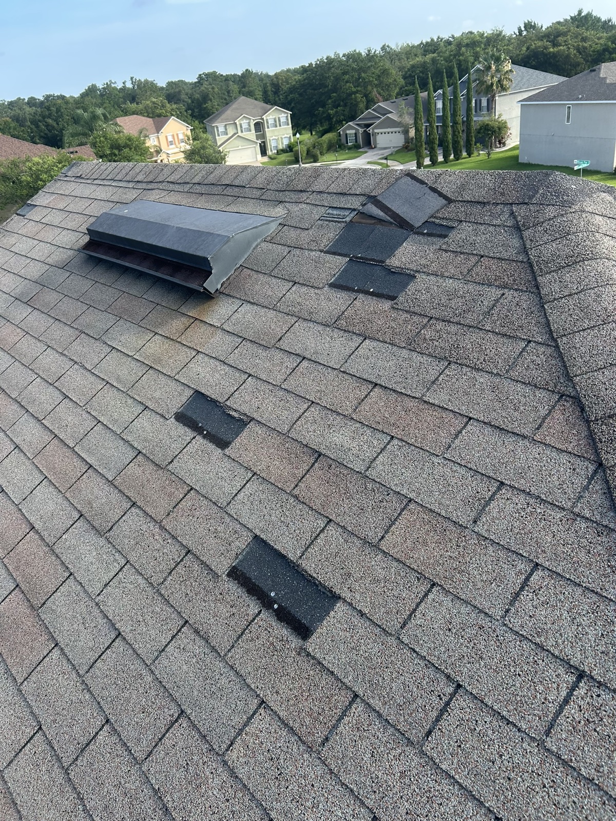 Shingle roof with temporary storm repair patches