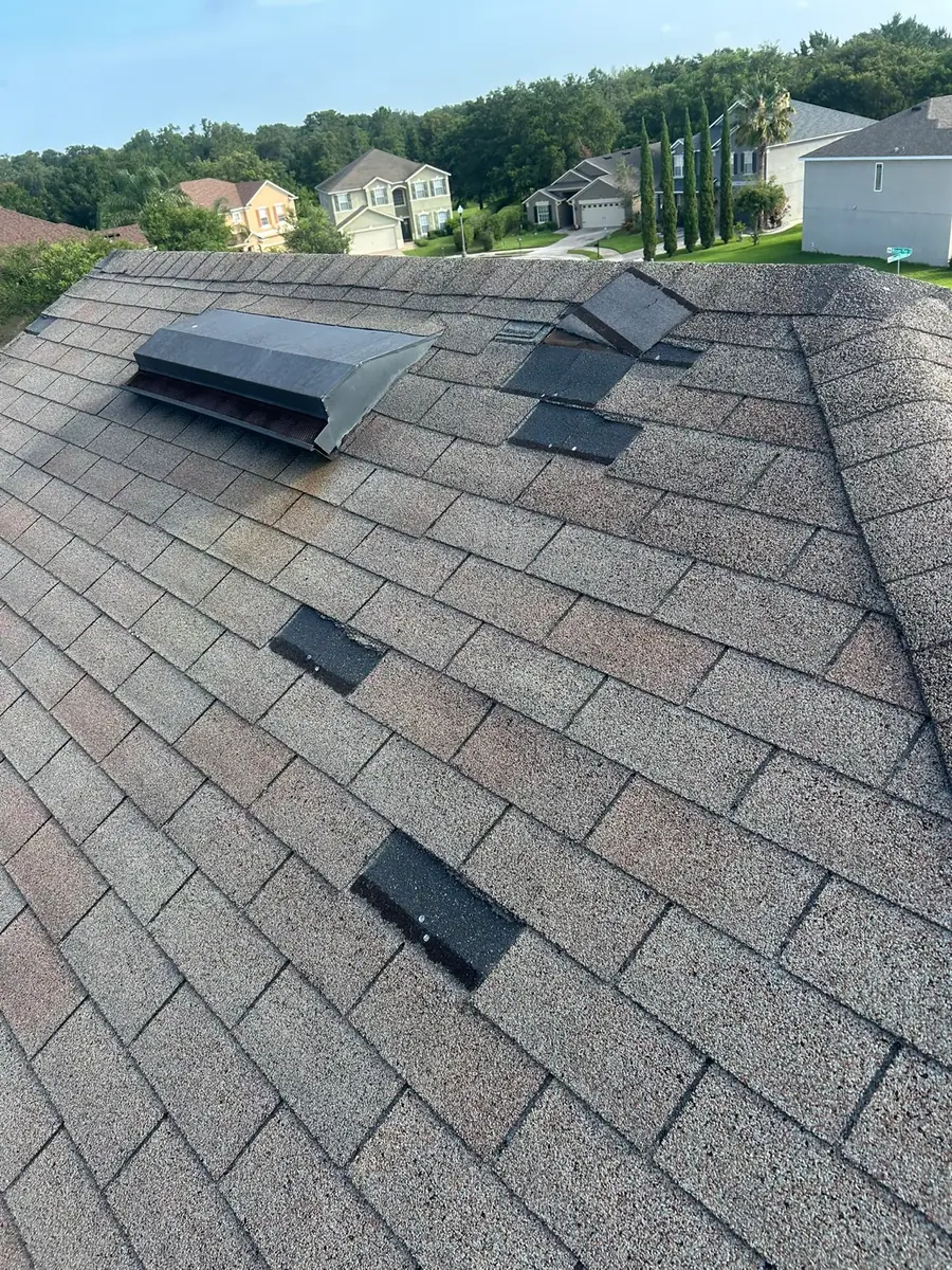 Shingle roof with temporary storm repair patches
