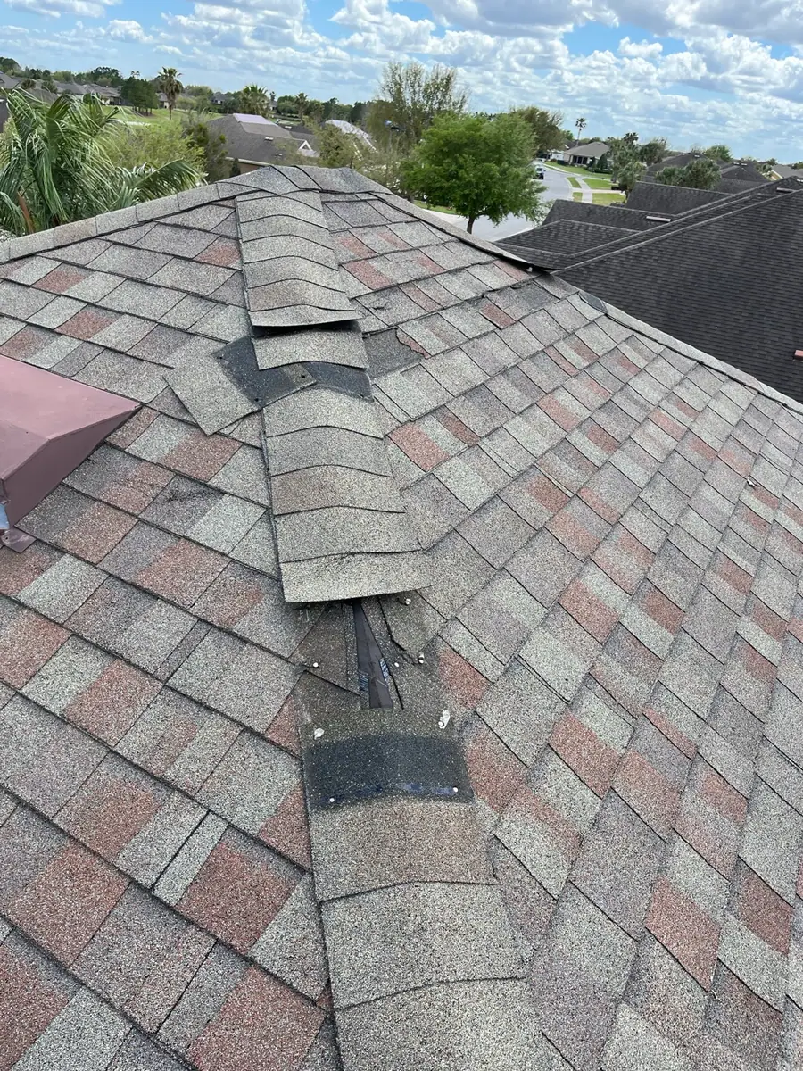 Lifted ridge cap and damaged shingles after wind