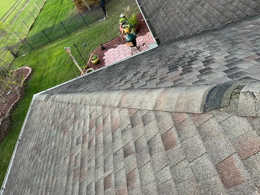 Shingle roof edge with storm damage near a gutter