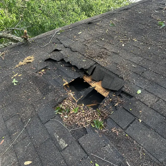 Storm-damaged shingle roof with debris and exposed decking